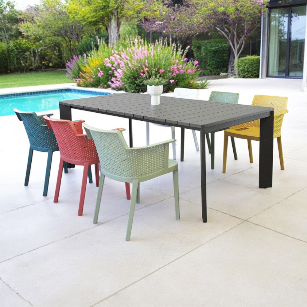 Tavolo da giardino CONNECTICUT ambientato in un patio moderno con piscina e sedute vivaci.