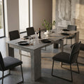 Tavolo consolle allungabile Dave in melaminico grigio effetto cemento allestito in una sala da pranzo moderna e luminosa.