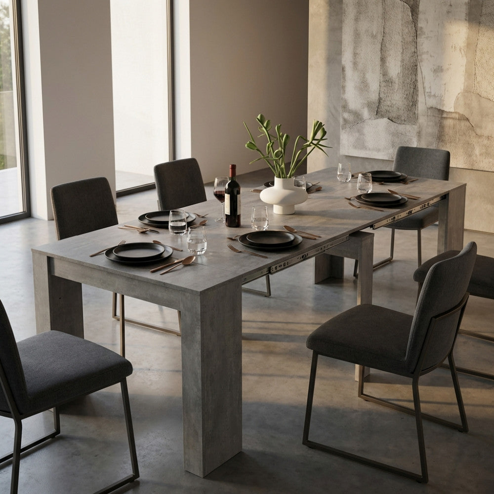 Tavolo consolle allungabile Dave in melaminico grigio effetto cemento allestito in una sala da pranzo moderna e luminosa.