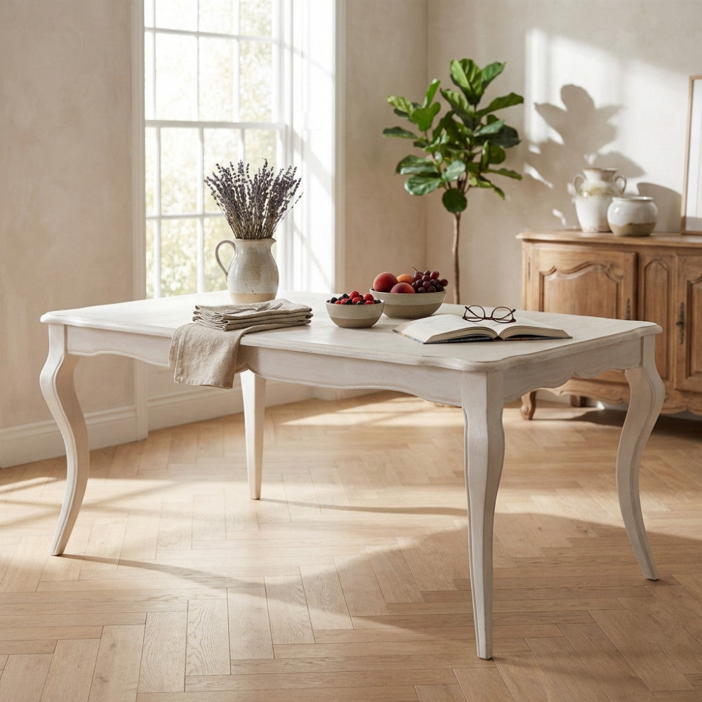 Tavolo da pranzo Cross in legno bianco allestito in un soggiorno luminoso con pavimento in parquet.