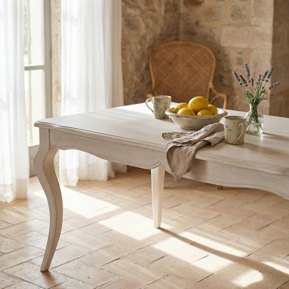 Dettaglio del tavolo da pranzo in legno bianco con limoni e lavanda, illuminato dalla luce naturale.