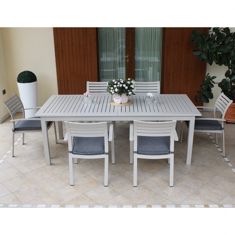 Tavolo da giardino Cuba allungabile in alluminio tortora ambientato in un patio elegante con sedute con cuscini grigi.