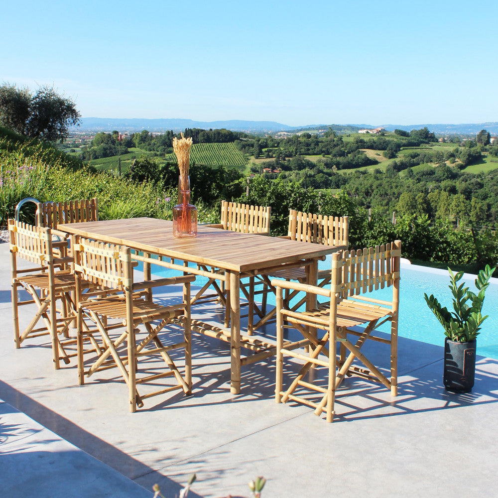 Allestimento da pranzo all'aperto con il tavolo da giardino Cuba Libre e sedie in legno abbinate con vista su un vigneto.