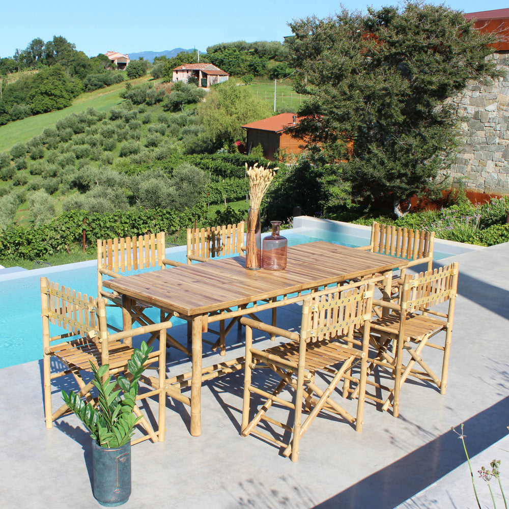 Prospettiva rialzata del tavolo da giardino Cuba Libre e sedie disposti su una terrazza soleggiata a bordo piscina.