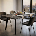 Tavolo da pranzo Dalbert in melaminico antracite nero allestito in una sala da pranzo moderna con vista panoramica.