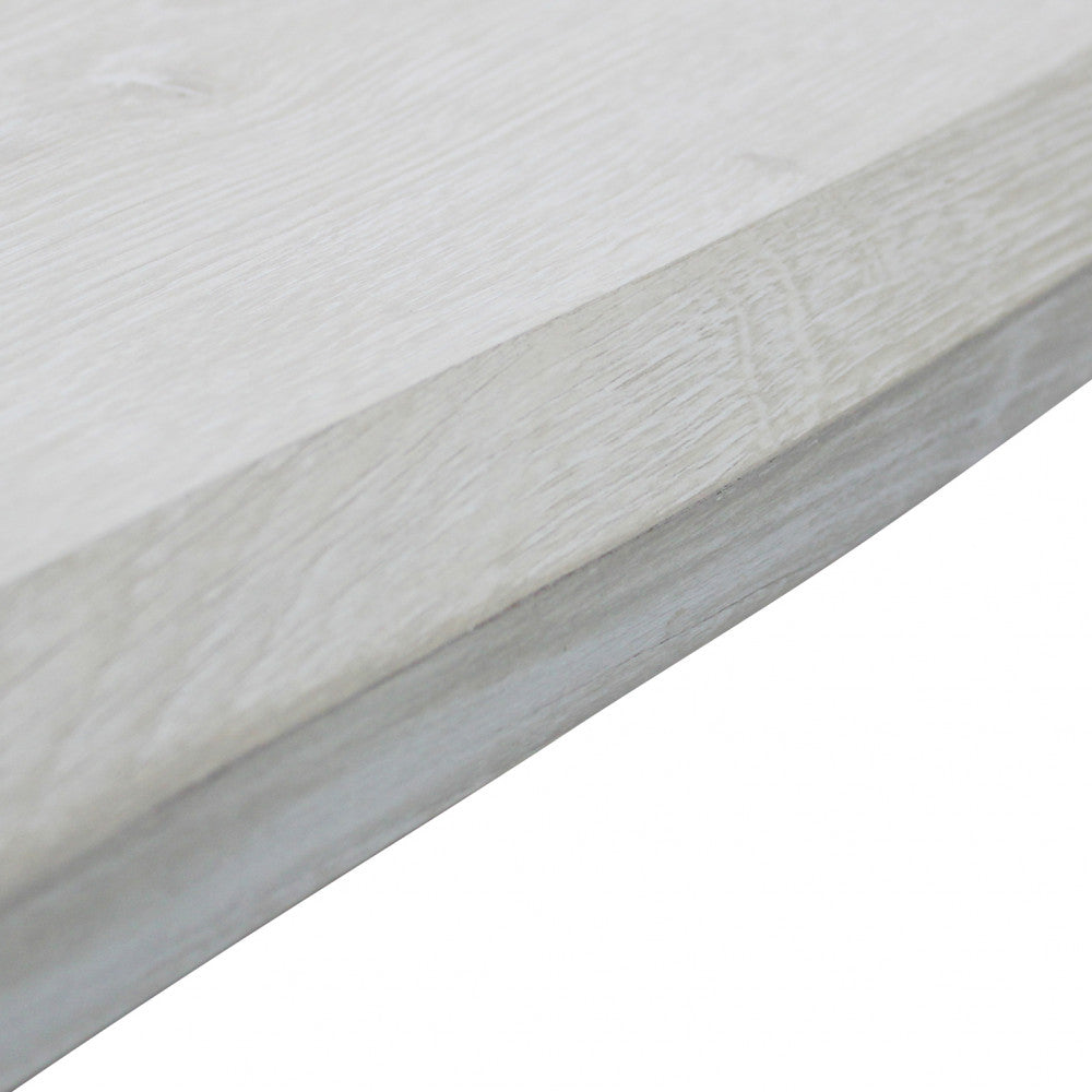 Primo piano del bordo sagomato del tavolo in melaminico con finitura effetto legno bianco.