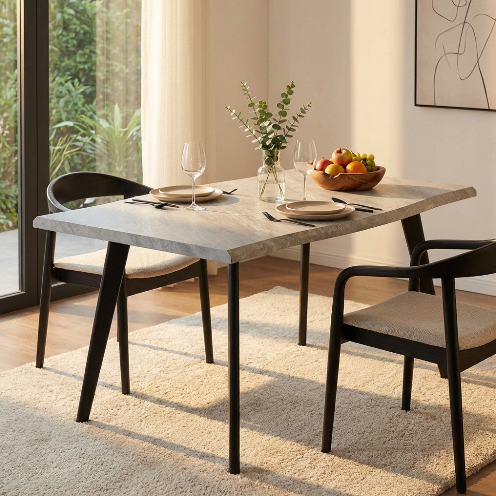Tavolo da pranzo Dalbert in melaminico effetto pietra grigio chiaro ambientato in una sala da pranzo moderna con sedie nere.