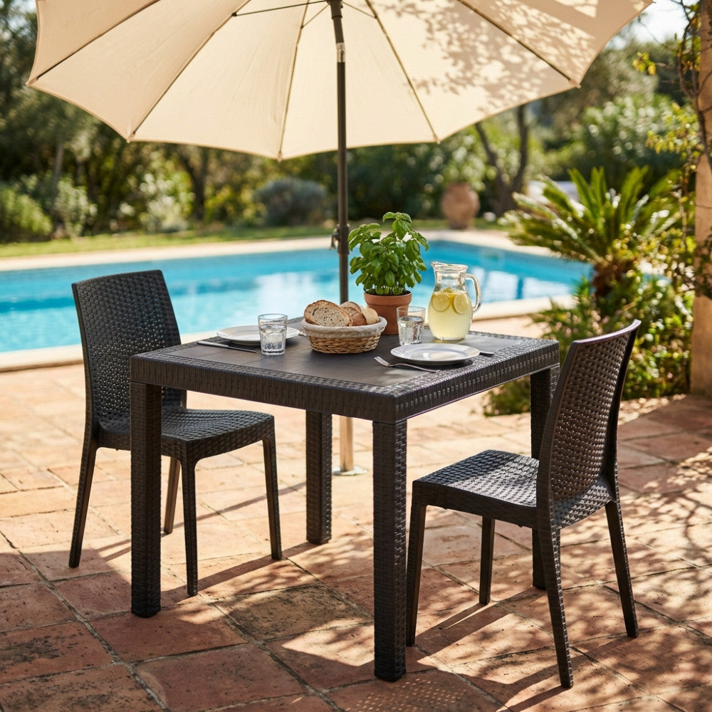 Tavolo da giardino Dallas in wicker antracite allestito a bordo piscina con sedute coordinate e ombrellone.