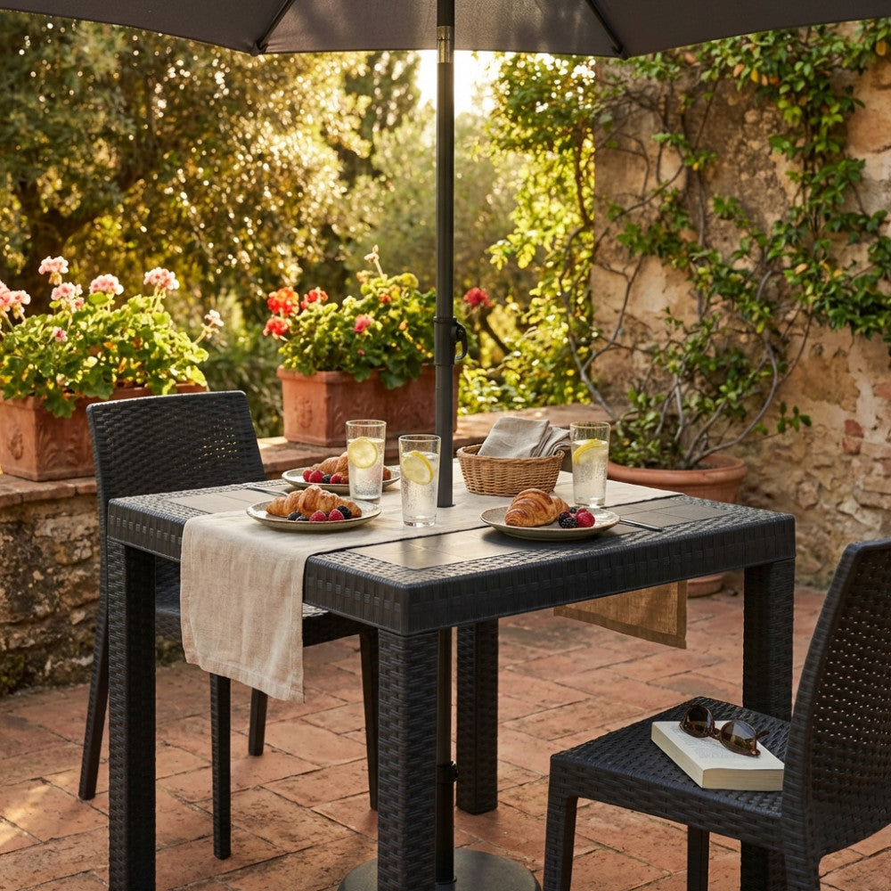 Dettaglio del tavolo da esterno Dallas 80x80 cm apparecchiato per la colazione in un patio rustico.