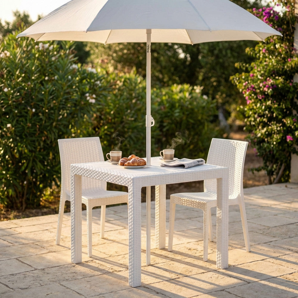 Tavolo da giardino Dallas in wicker bianco allestito per la colazione sotto un ombrellone.