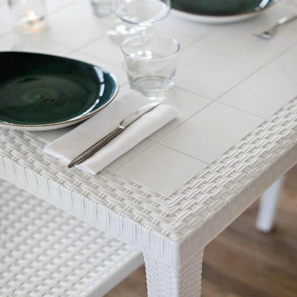 Particolare della superficie intrecciata del tavolo Dallas con mise en place elegante.