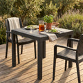 Tavolo da giardino Dallas 80x80 in wicker taupe allestito per un pranzo all'aperto su una terrazza in legno.