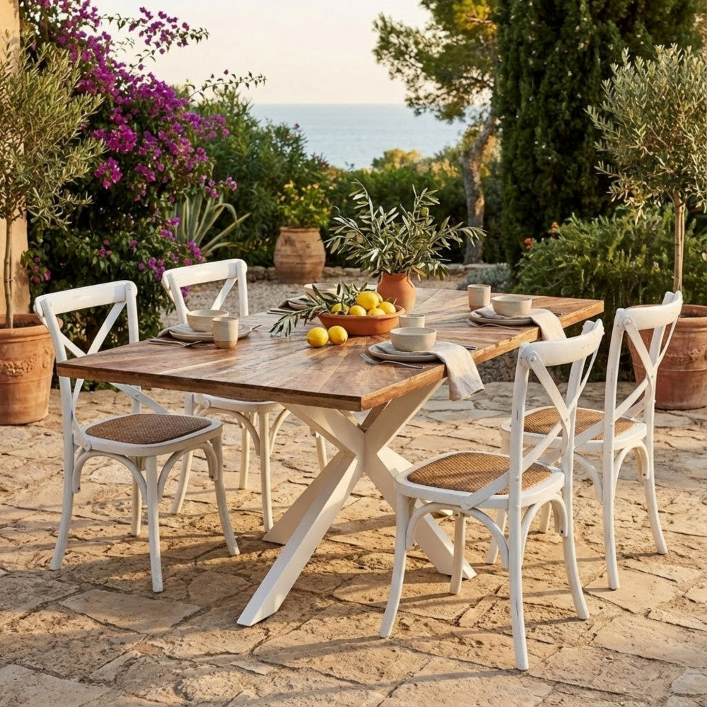 Tavolo da pranzo Dannie ambientato in un patio esterno soleggiato con sedie bianche incrociate.