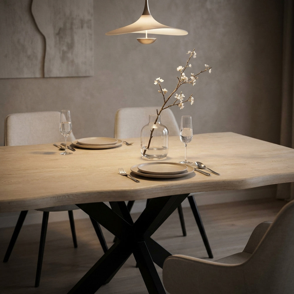 Dettaglio del tavolo da pranzo Floyd apparecchiato con calici e vaso decorativo sotto una lampada di design.