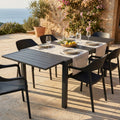 Tavolo da giardino Formentera in alluminio antracite allestito per un pranzo all'aperto su una terrazza in pietra con vista mare.