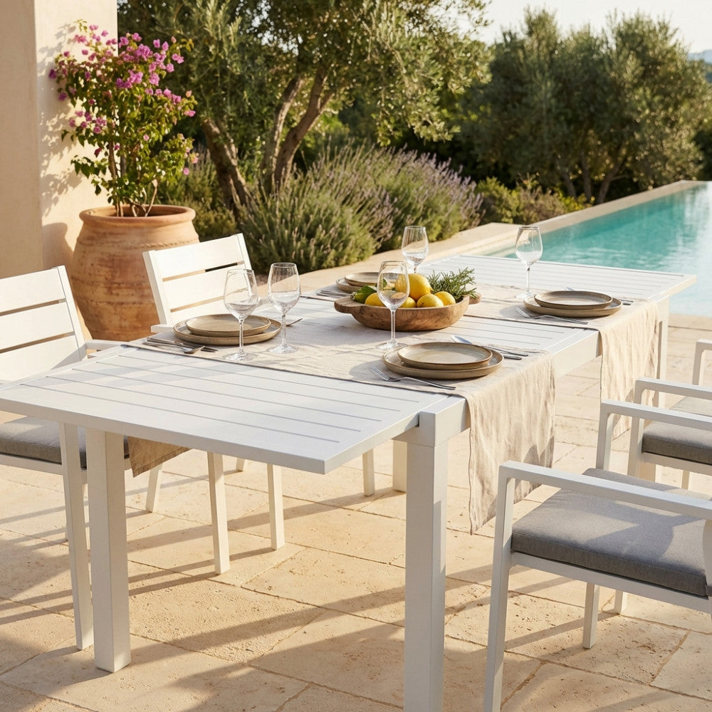 Dettaglio del tavolo Formentera apparecchiato con runner in lino e ceramiche artigianali, immerso in un lussuoso patio esterno.