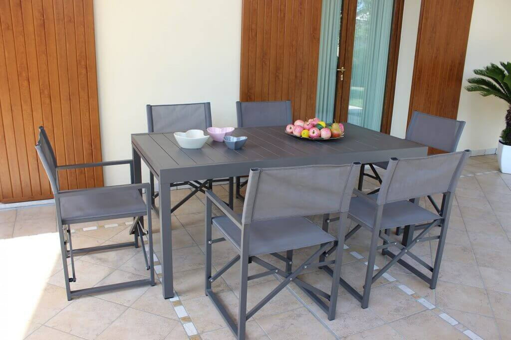Tavolo da esterno Formentera con sedie abbinate e cesto di frutta su una terrazza pavimentata.