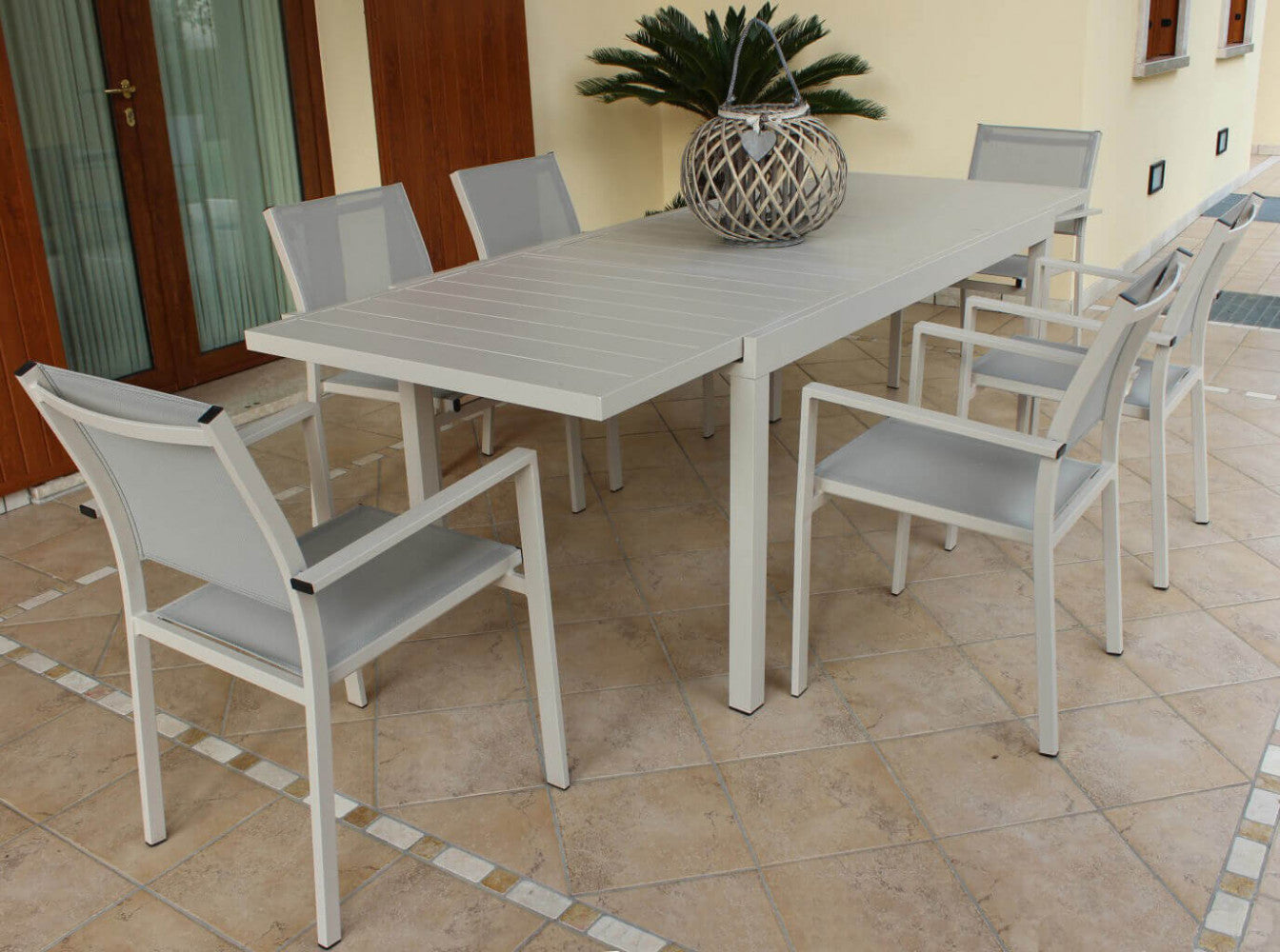 Prospettiva angolare del tavolo da giardino Formentera allungabile, inserito in un contesto architettonico residenziale.