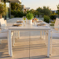 Tavolo da giardino allungabile Freeport in alluminio bianco e pietra sinterizzata, allestito per un pranzo all'aperto su un patio soleggiato.