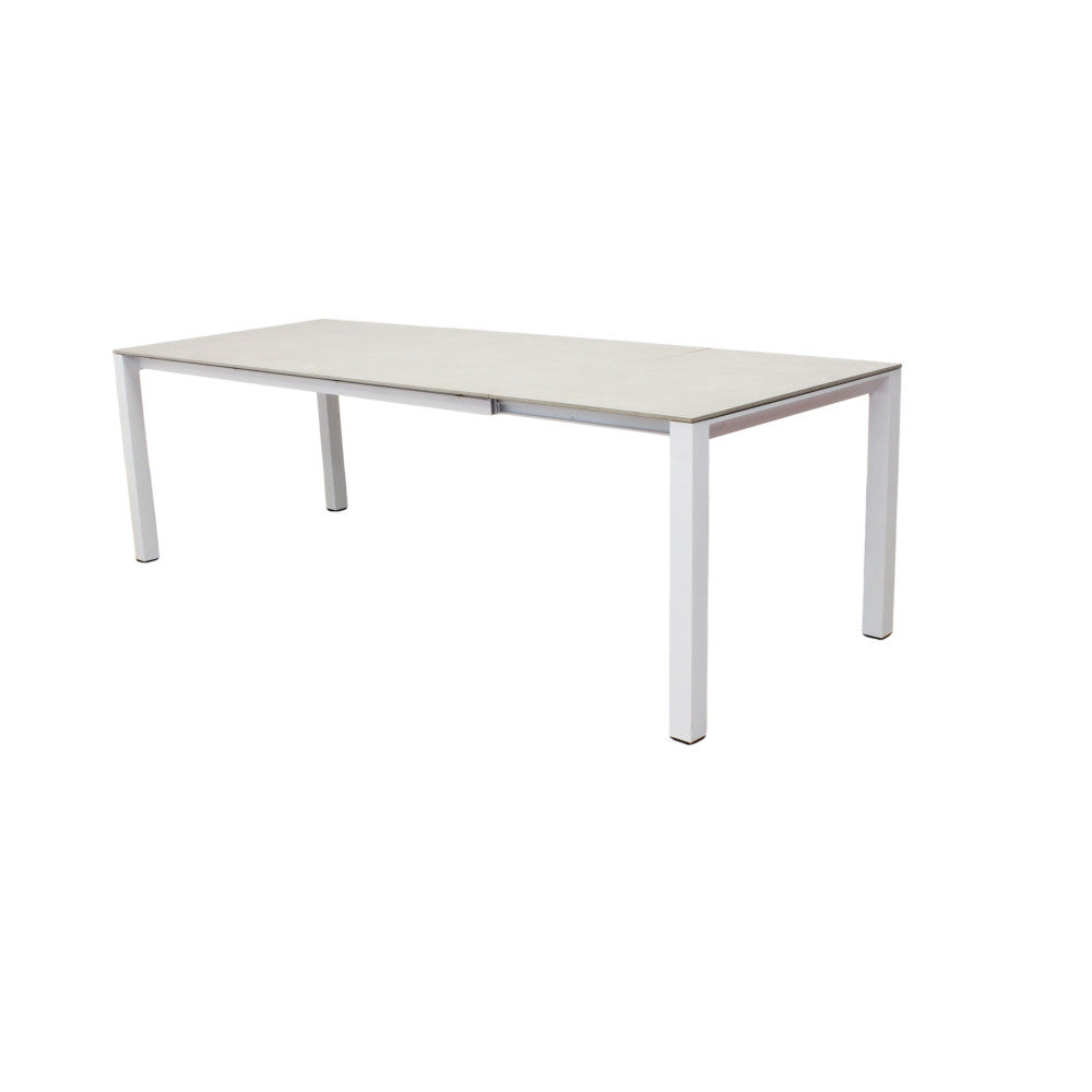 Tavolo da giardino Freeport isolato su fondo bianco, che mostra la struttura in alluminio bianco e il piano in pietra sinterizzata grigio chiaro.