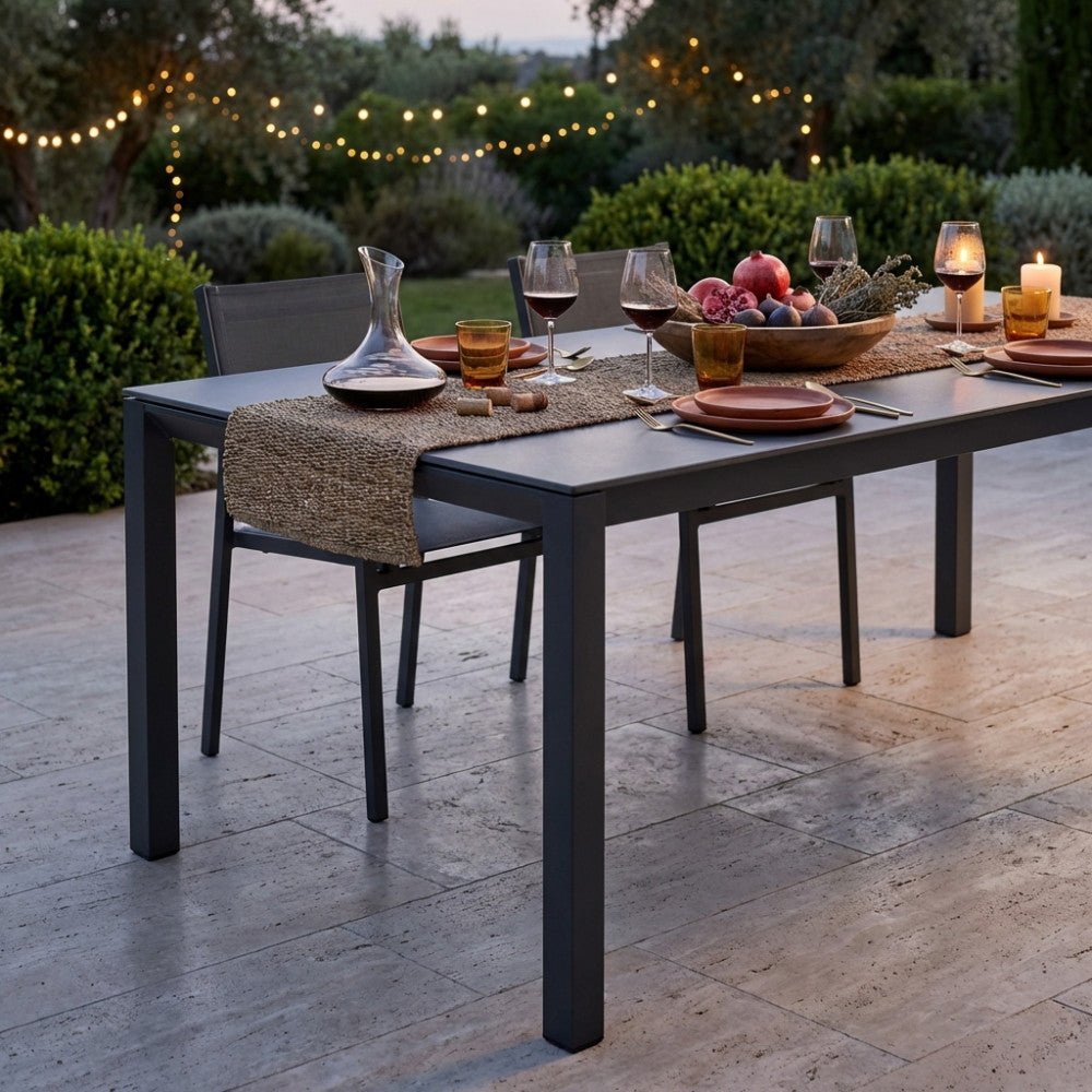 Dettaglio del tavolo Freeport apparecchiato al tramonto con calici di vino e decorazioni naturali.