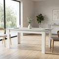 Tavolo da pranzo allungabile Gemma effetto cemento ambientato in una sala luminosa con sedie in legno.