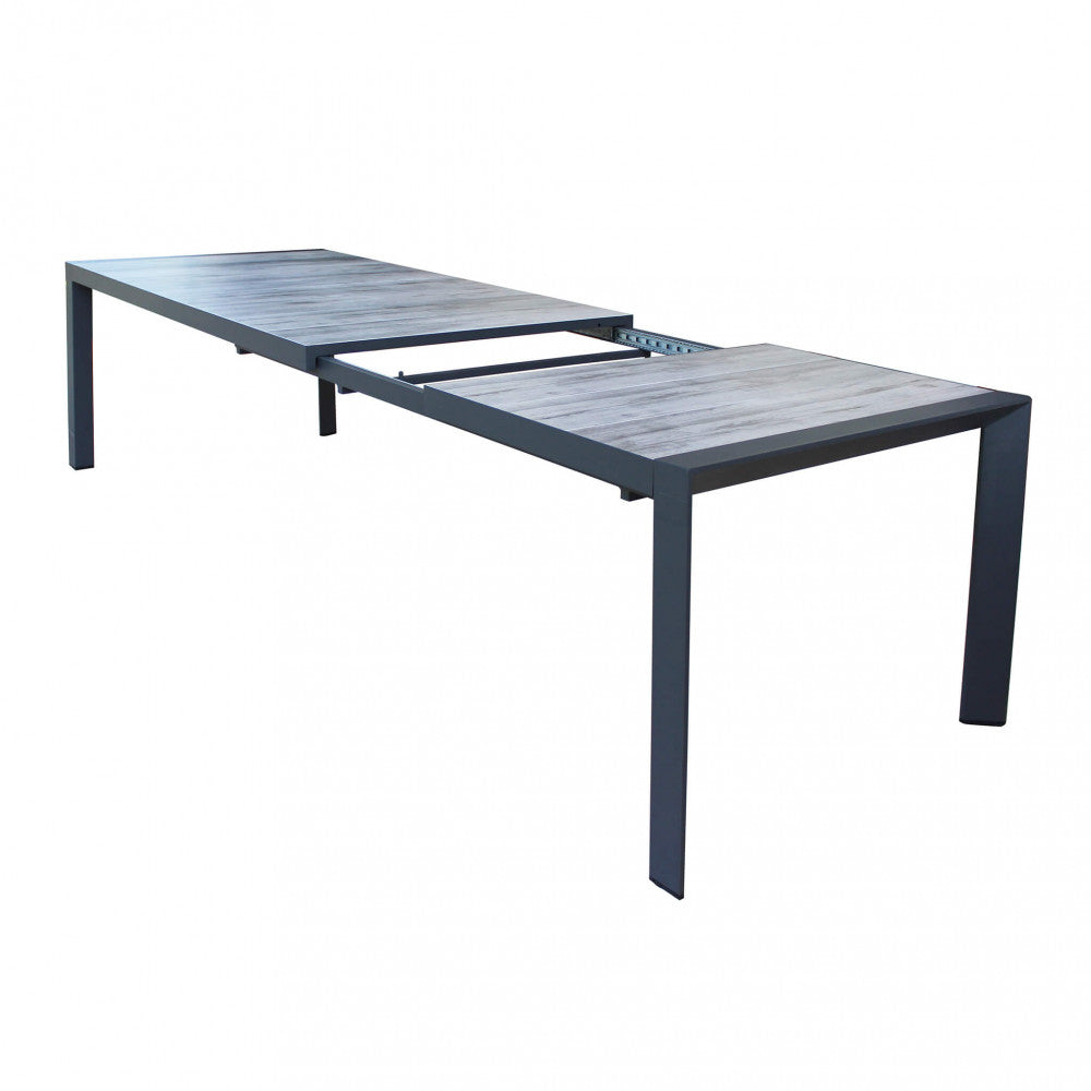 Tavolo Portland con piano in gres esteso su un patio arredato.