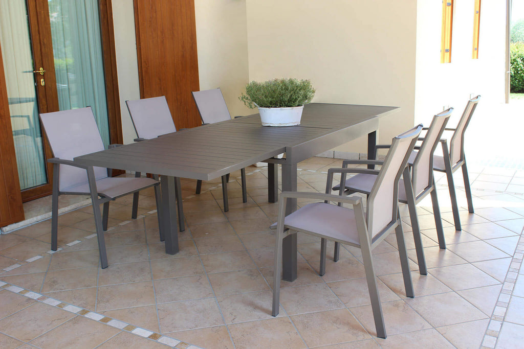 Tavolo da giardino Hawaii allungato in alluminio taupe, ambientato in un portico elegante con sedie coordinate.
