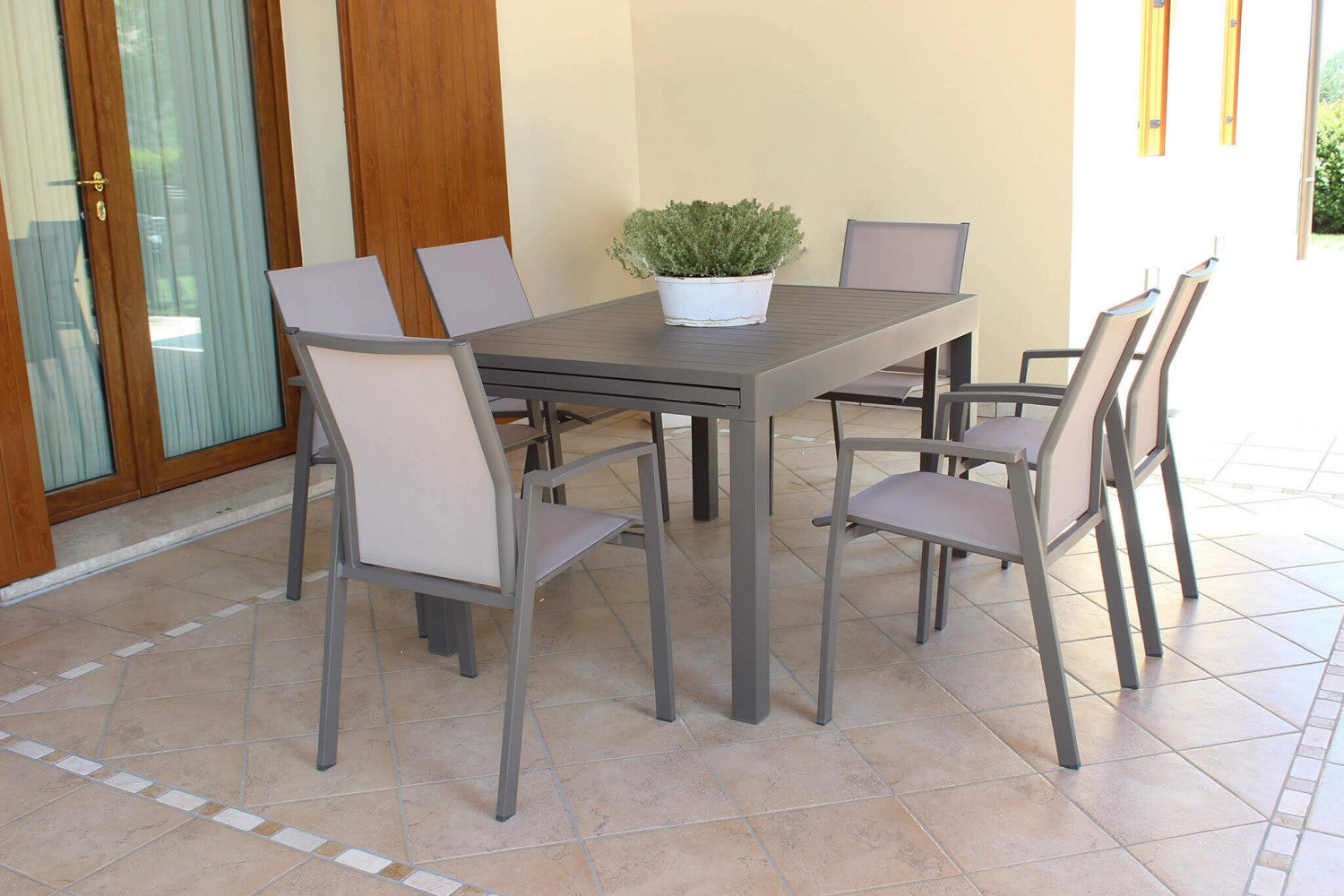 Tavolo da giardino Hawaii chiuso in alluminio taupe, allestito in un patio coperto con sedute in tessuto.