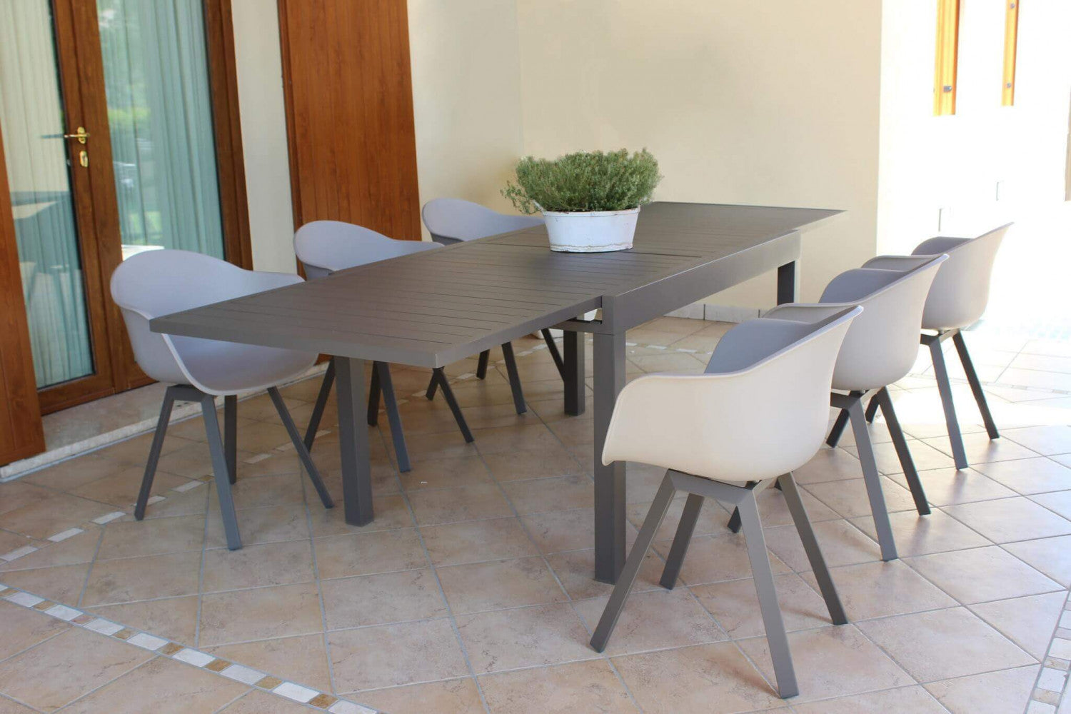 Tavolo da giardino Hawaii allungato in alluminio taupe, abbinato a poltroncine di design in un ambiente outdoor raffinato.