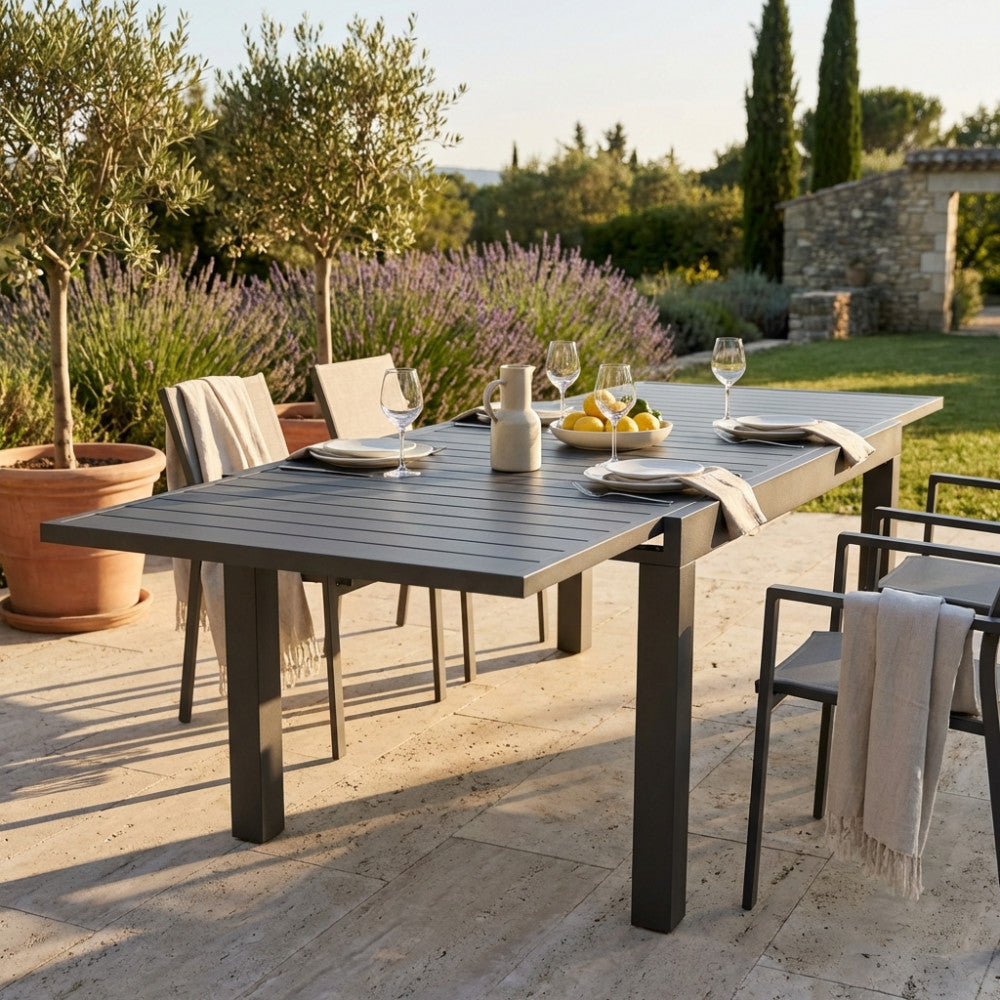 Tavolo da giardino Hawaii allungato, allestito per un pranzo all'aperto in un lussuoso giardino mediterraneo.