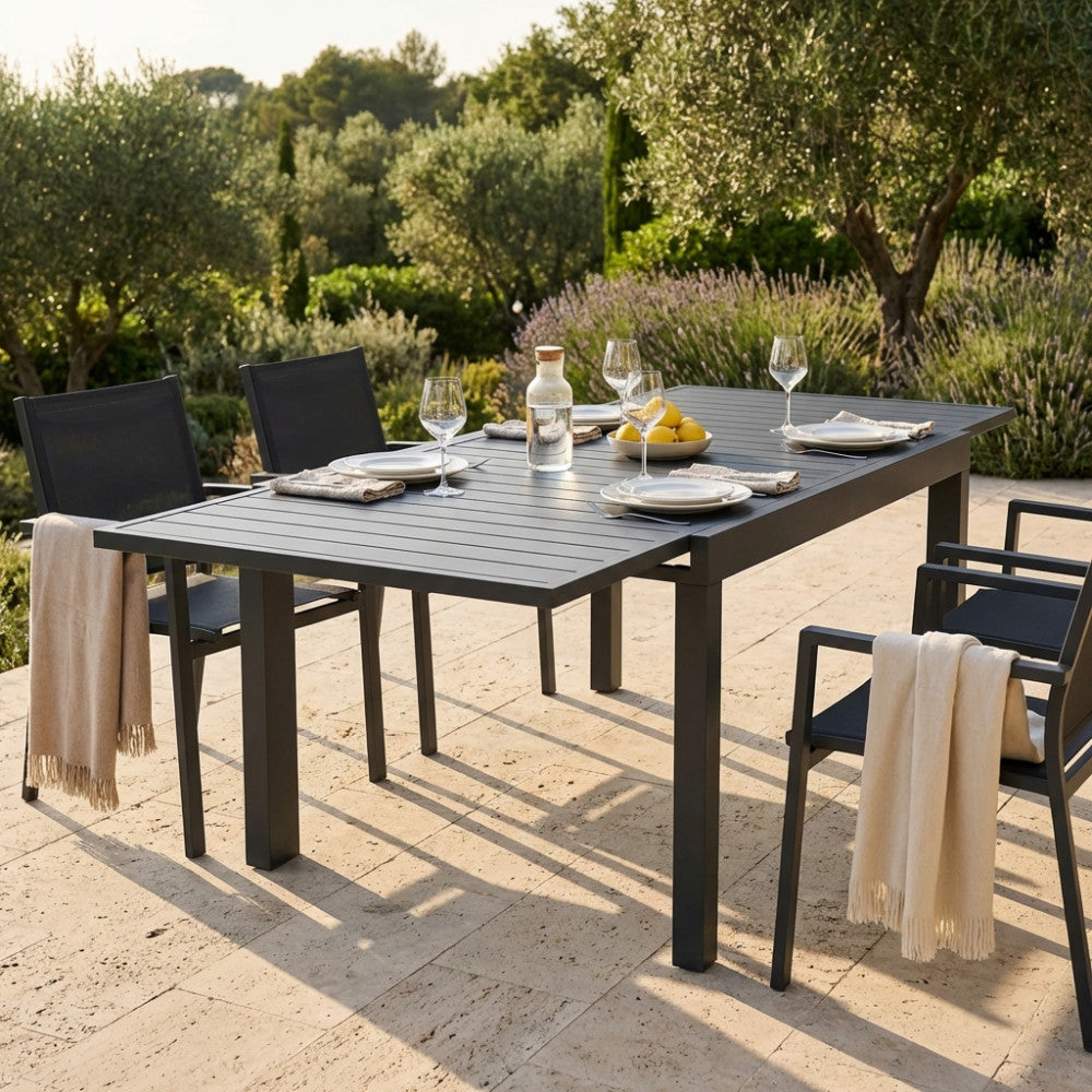 Dettaglio del tavolo da giardino Hawaii in alluminio taupe con sedute abbinate in un patio soleggiato.