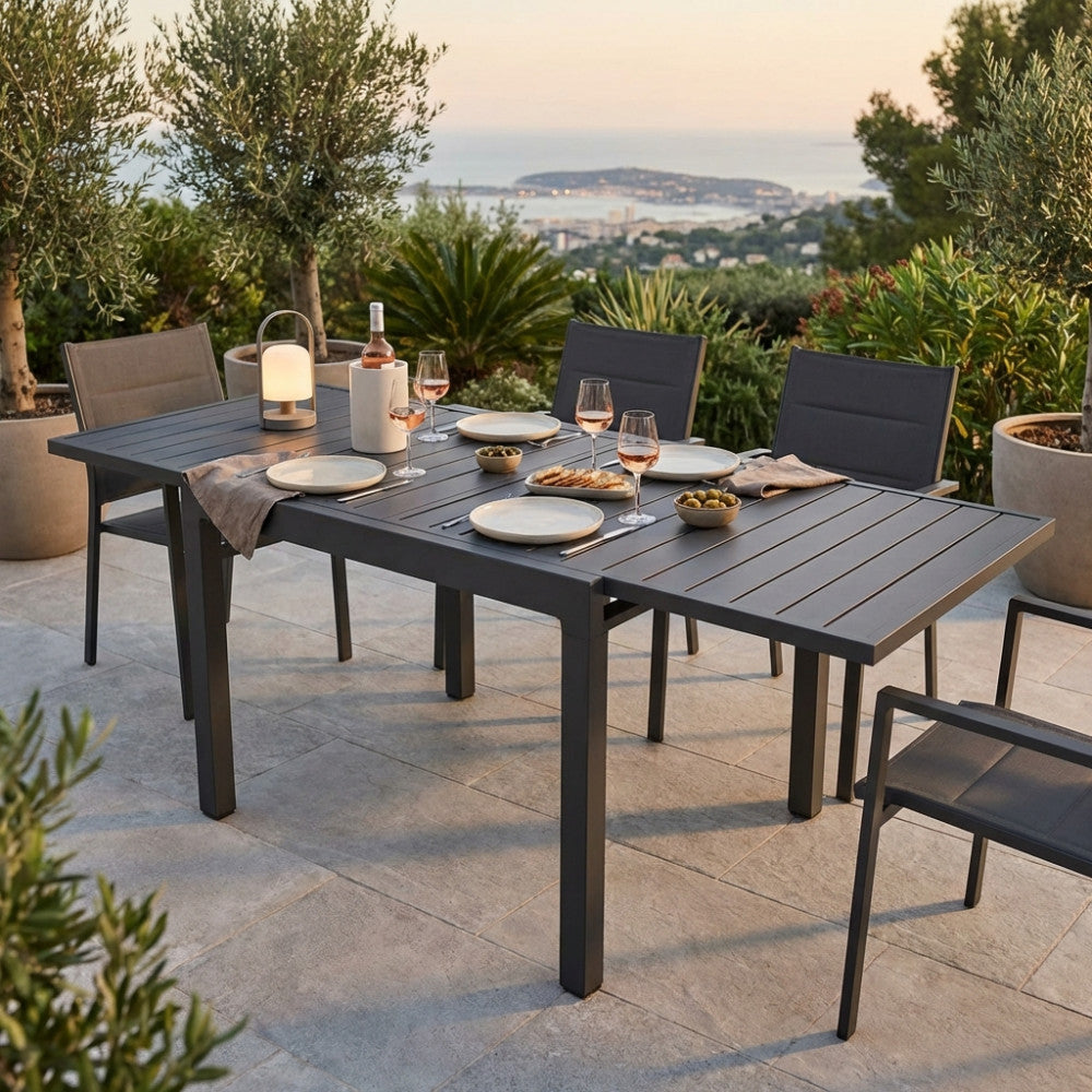 Un elegante allestimento serale con il tavolo da pranzo allungabile Hawaii, adornato con vino e stuzzichini sullo sfondo di un tramonto panoramico.