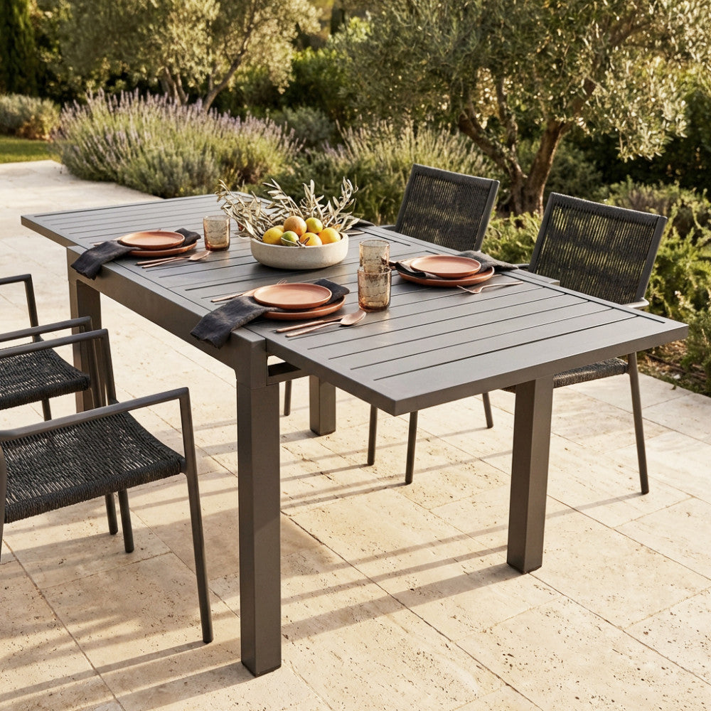 Tavolo da giardino allungabile Hawaii in alluminio taupe, allestito per una cena elegante all'aperto con sedute in corda.