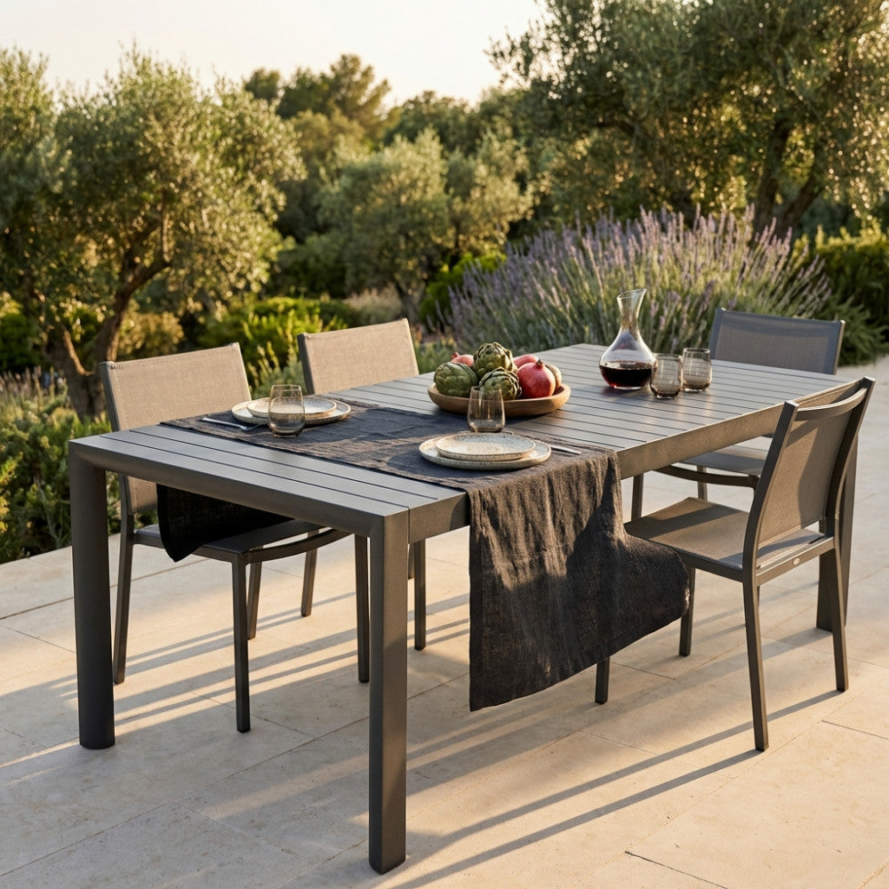 Dettaglio del tavolo Houston con runner in lino scuro e decorazioni naturali su terrazza.