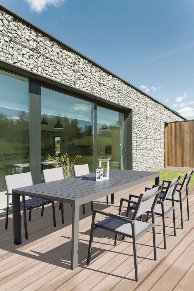 Tavolo da giardino allungabile Houston in alluminio taupe ambientato su un patio in legno con sedute abbinate.