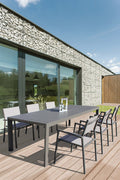 Tavolo da giardino allungabile Houston in alluminio taupe ambientato su un patio in legno con sedute abbinate.