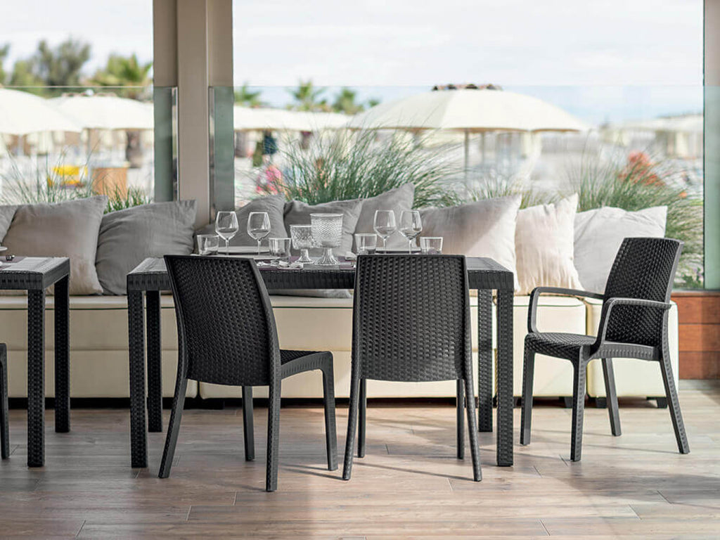 Ambientazione contract di lusso con il tavolo Houston in wicker antracite su una terrazza panoramica.