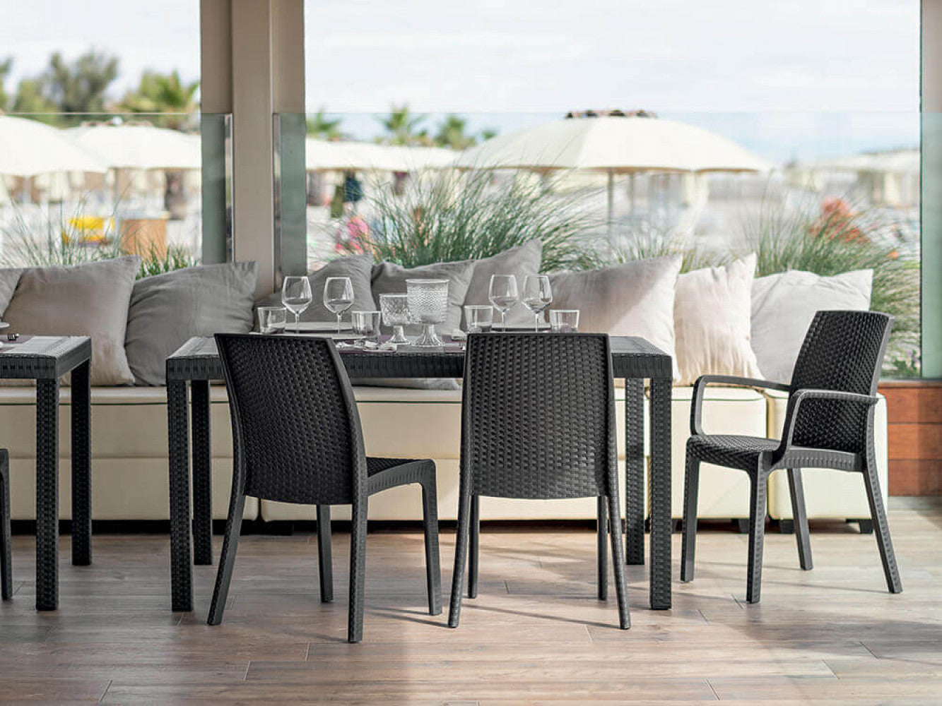 Ambientazione contract di lusso con il tavolo Houston in wicker antracite su una terrazza panoramica.