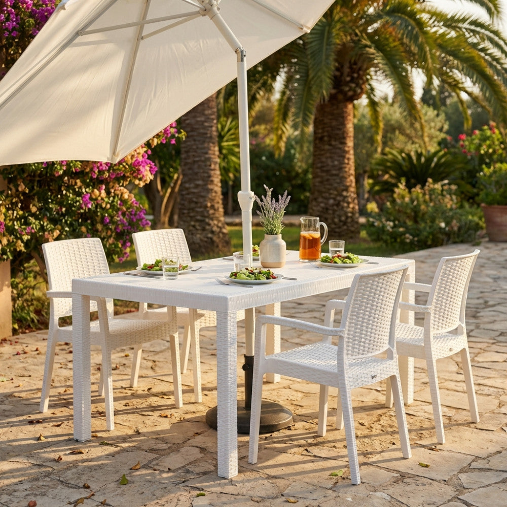 Tavolo rettangolare Houston in wicker bianco ambientato in un rigoglioso giardino mediterraneo durante un pranzo estivo.
