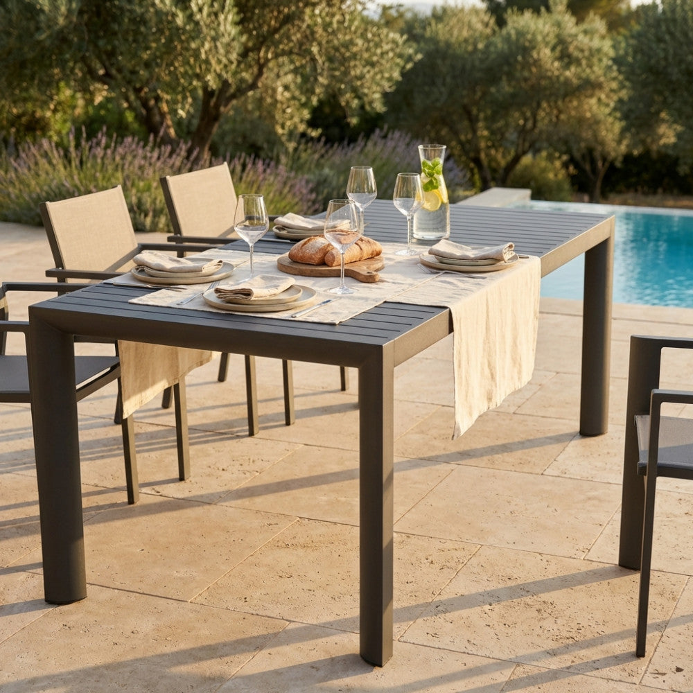 Tavolo da giardino allungabile Houston in alluminio antracite allestito per un pranzo all'aperto a bordo piscina.