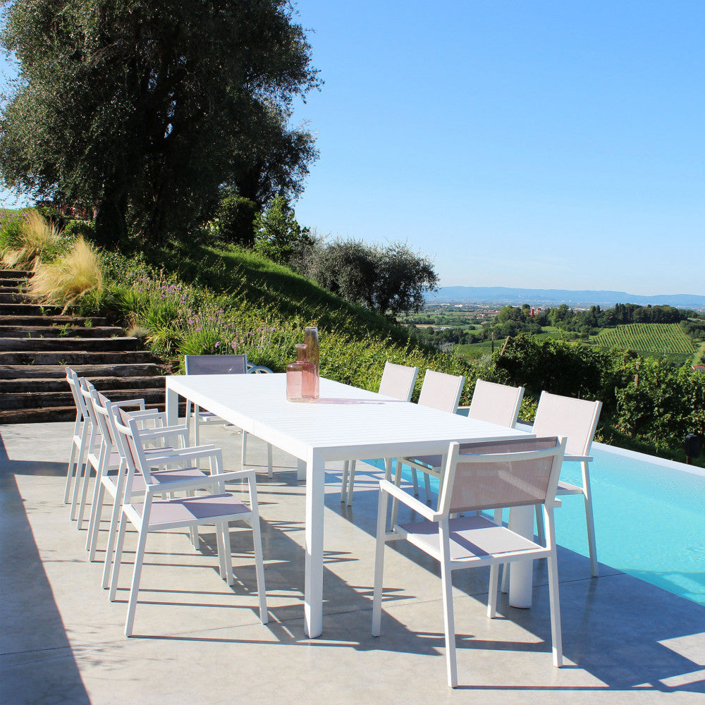 Tavolo da giardino Houston in alluminio bianco esteso a bordo piscina con paesaggio collinare sullo sfondo.
