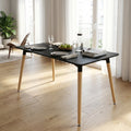 Tavolo da pranzo Lione nero con gambe in legno, allestito in un soggiorno luminoso con sedute di design.