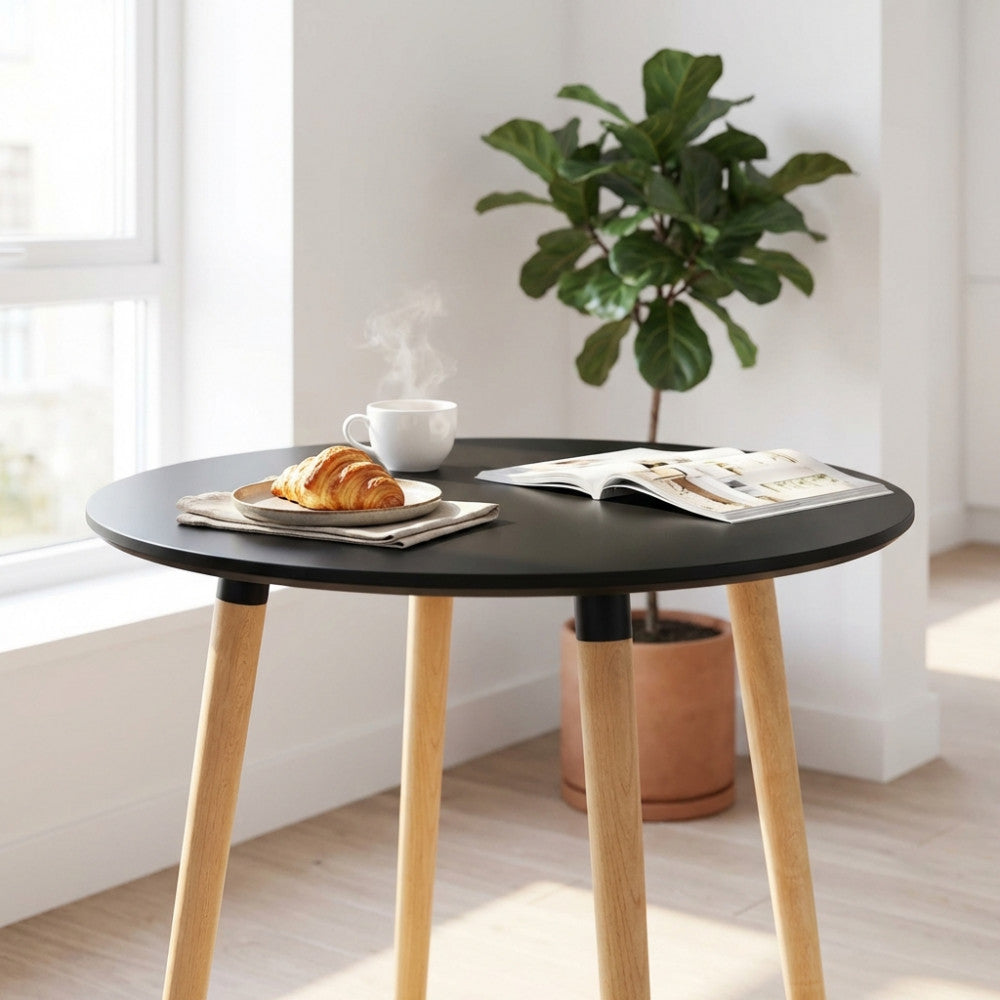 Dettaglio del tavolo LIONE nero con tazza di caffè e croissant, affiancato da una pianta d'appartamento.