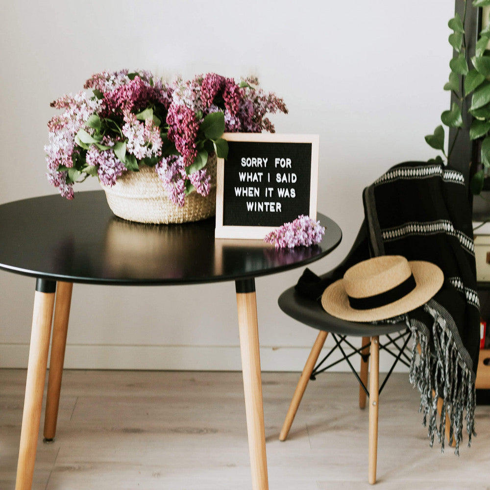Tavolo moderno LIONE decorato con fiori di lillà e una lavagna con scritte, in un contesto living elegante.