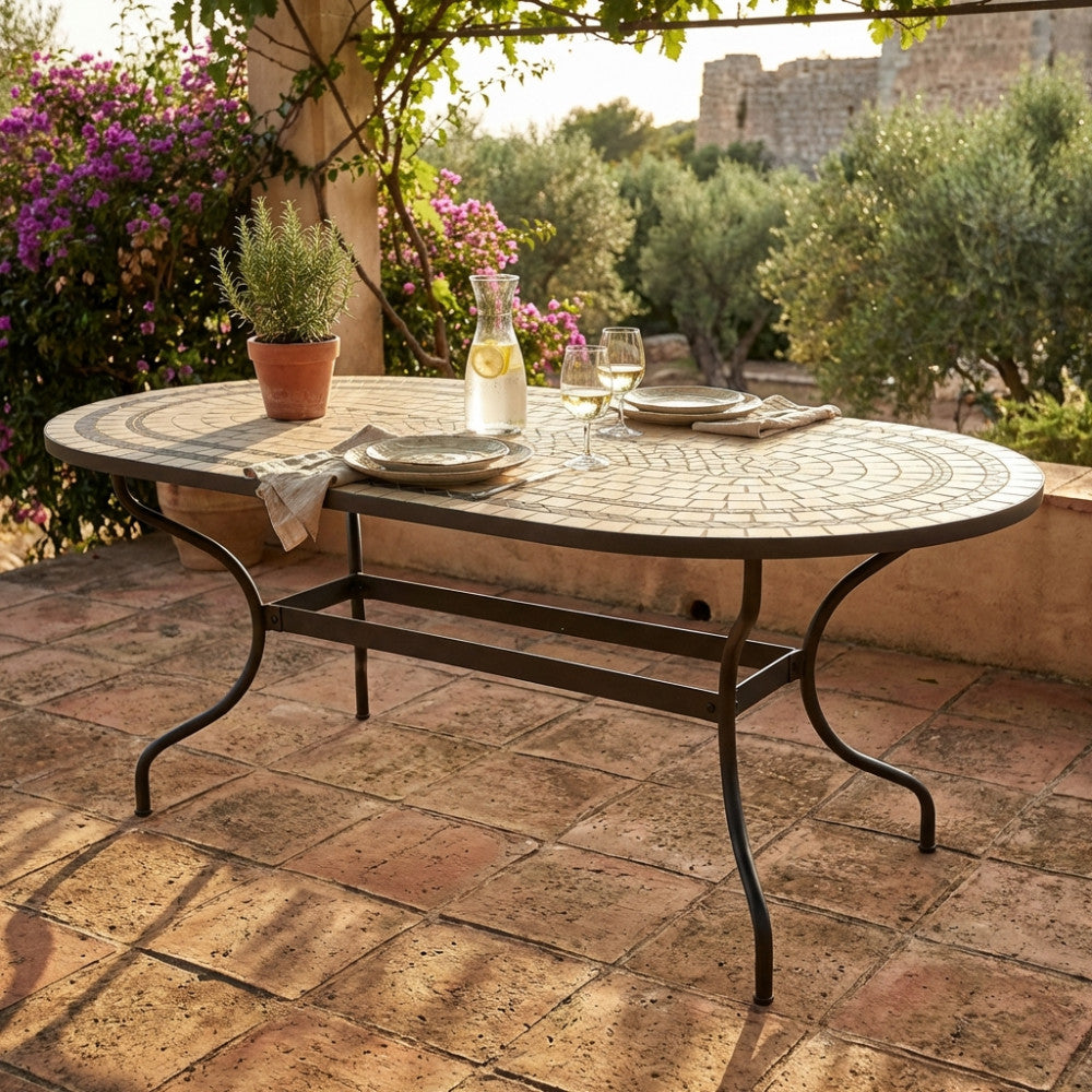 Tavolo da giardino ovale Dedalo in ceramica con mosaico, elegantemente allestito con bicchieri su un patio in cotto.