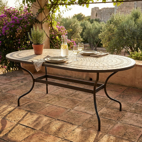 Tavolo da giardino ovale Dedalo in ceramica con mosaico, elegantemente allestito con bicchieri su un patio in cotto.