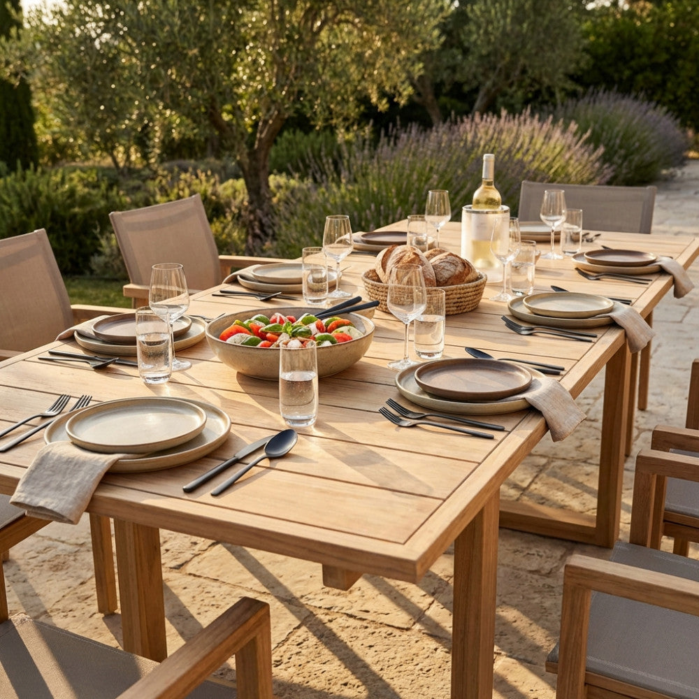 Tavolo da giardino in teak Parker apparecchiato elegantemente con sedie moderne, immerso in un uliveto.