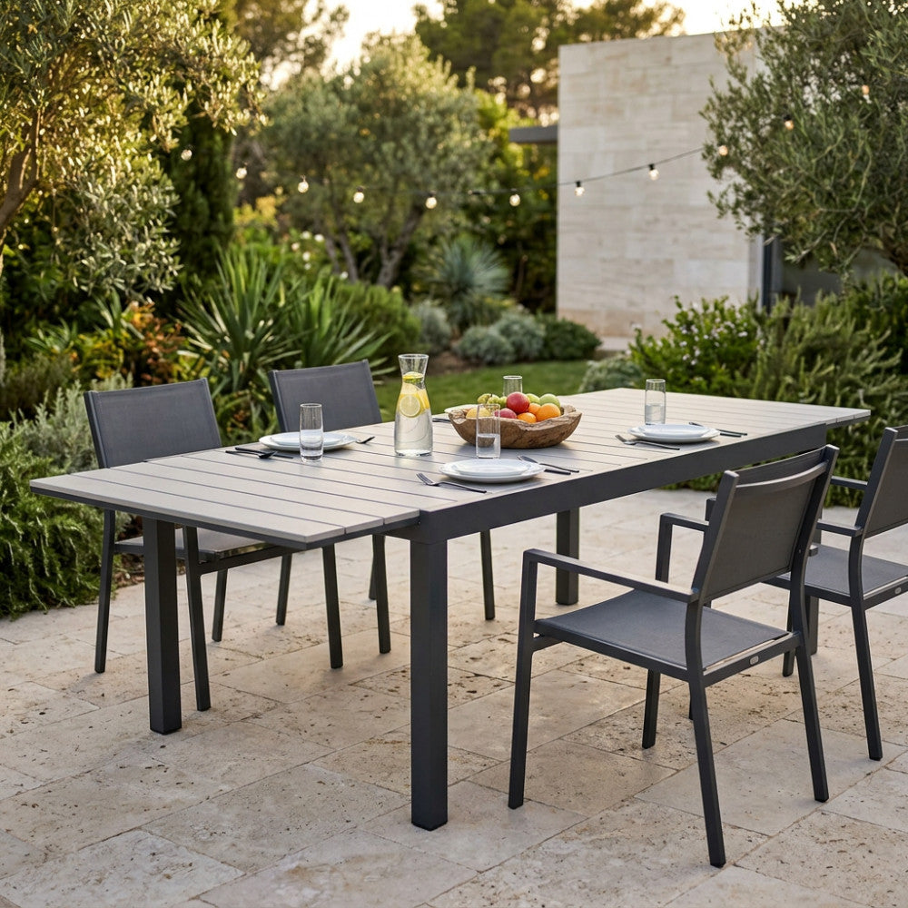 Dettaglio del tavolo Pental in polywood grigio con sedute abbinate su una terrazza in pietra.