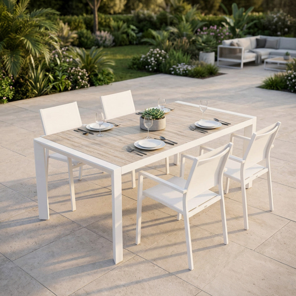 Set da pranzo all'aperto con tavolo estensibile Portland e sedie bianche su una luminosa terrazza in pietra.